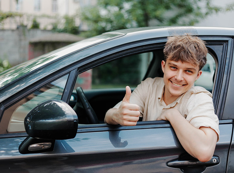 Un jeune conducteur au volant de sa voiture assurée